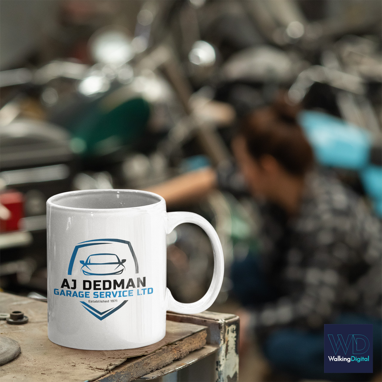 AJ Dedmans Garage Services branding on a coffee mug in a garage